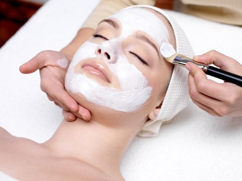 Woman relaxing while a facial mask is brushed on