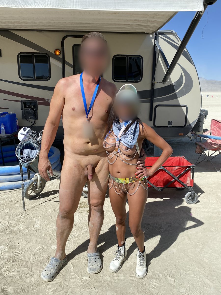 A nude man and a woman in festival wear smiling together outdoors
